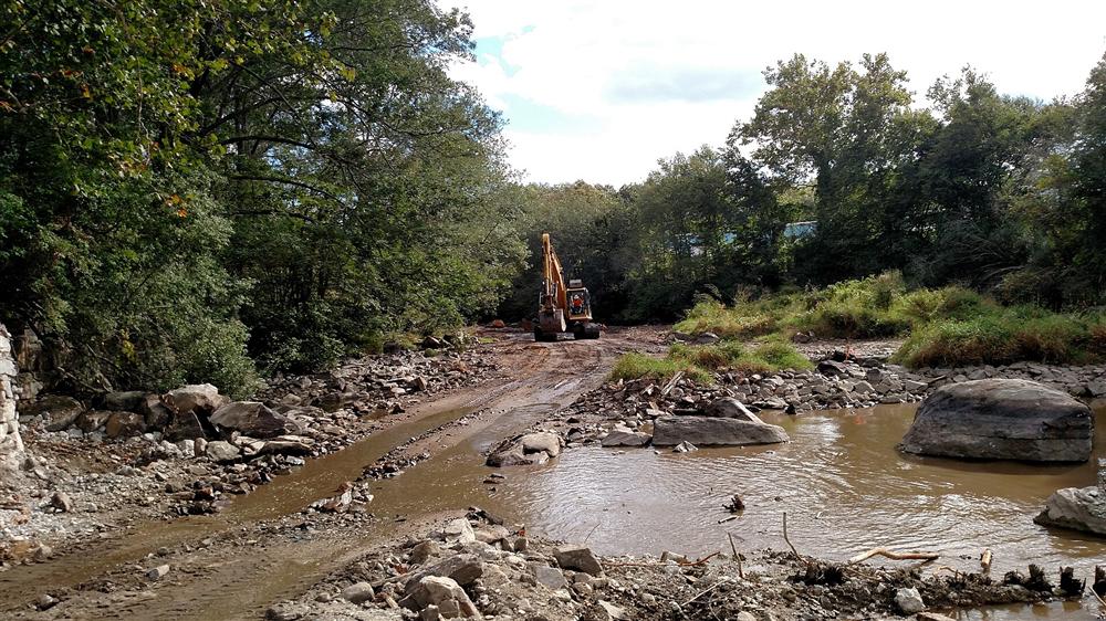 Excavator equipment working along a river bed during a waterway restoration project